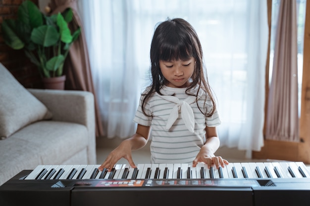 Cute little girl plays a keyboard instrument