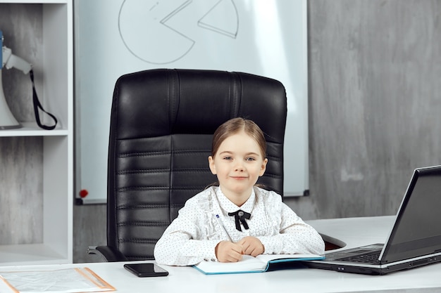 A cute little girl portrays the boss posing in front of the camera