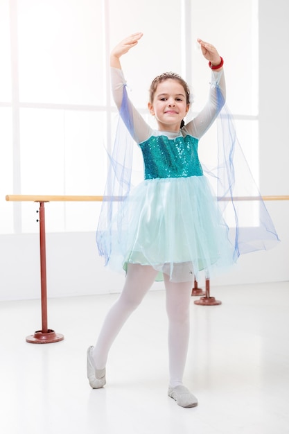 Photo cute little girl practicing ballet in dance studio and looking at camera.