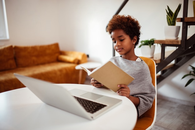 Cute little girl reading a book at home.