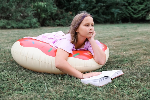 Cute little girl reading book outdoors. Summertime rest