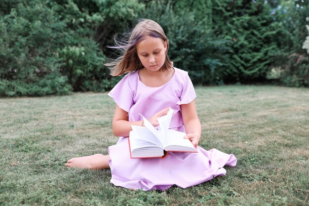 Cute little girl reading book outdoors. Summertime rest