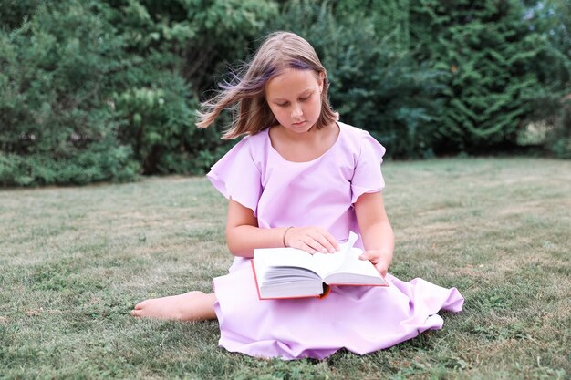 Cute little girl reading book outdoors. Summertime rest