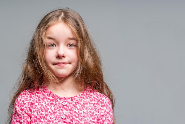 Cute little girl in a red dress on a gray background Isolated