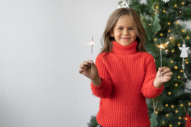 Photo cute little girl in a red sweater on christmas