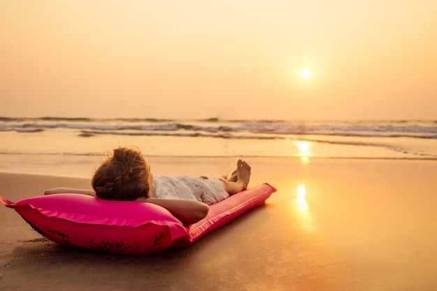 Фото Милая маленькая девочка отдыхает на надувном матрасе в летние каникулы закат пляж тропический рай море океан spf солнцезащитный крем фриланс фриланс