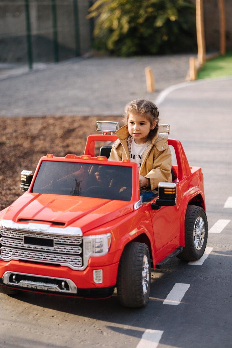 かわいい女の子がおもちゃで赤い電気自動車ジープ愛らしい小さな女の子の道にミニシティに乗る