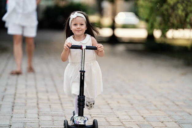 Cute little girl riding on kick scooter at park