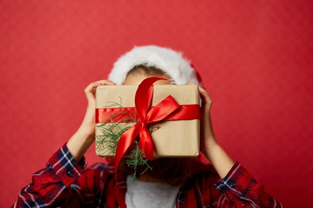그녀의 얼굴 앞에서 크리스마스 선물을 들고 산타 모자에 귀여운 소녀