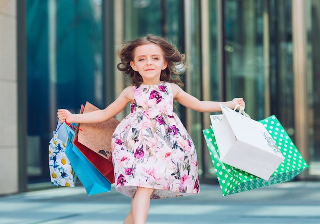 ショッピングでかわいい女の子。買い物袋を持つ子供の肖像画。ショッピング。女の子。