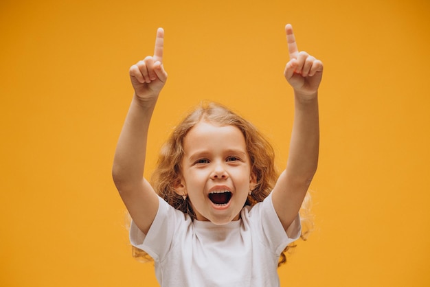 Cute little girl showing emotions, isolated on yellow background