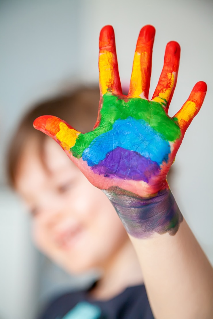 Photo cute little girl showing her hand with rainbow painted on her palm