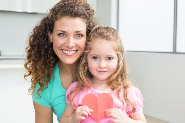 Cute little girl showing paper heart with mother 