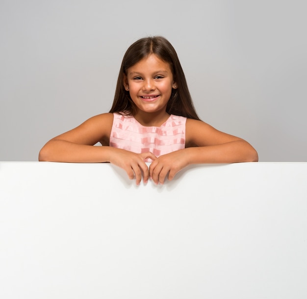 Cute little girl showing a white empty panel