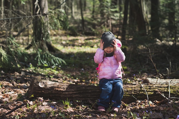 Photo cute little girl sit on log in forest