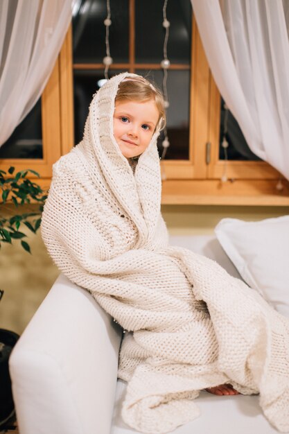 Photo cute little girl sits in her room on a windowsill at night.