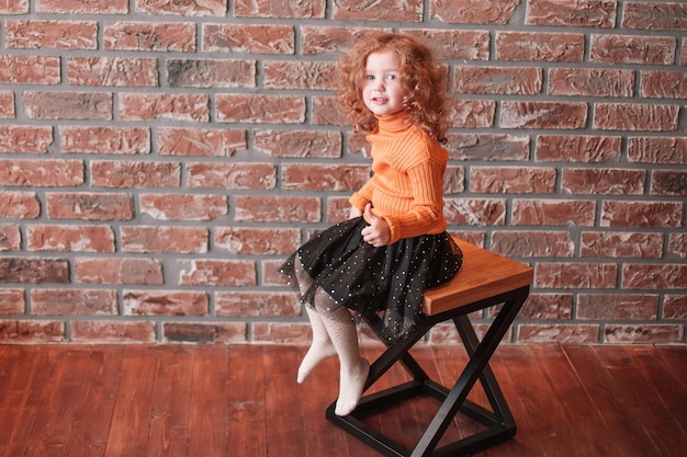 Cute little girl sitting on a chair in a new living room