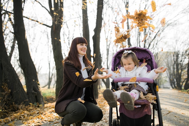 cute little girl sitting in purple baby stroller next to her mother