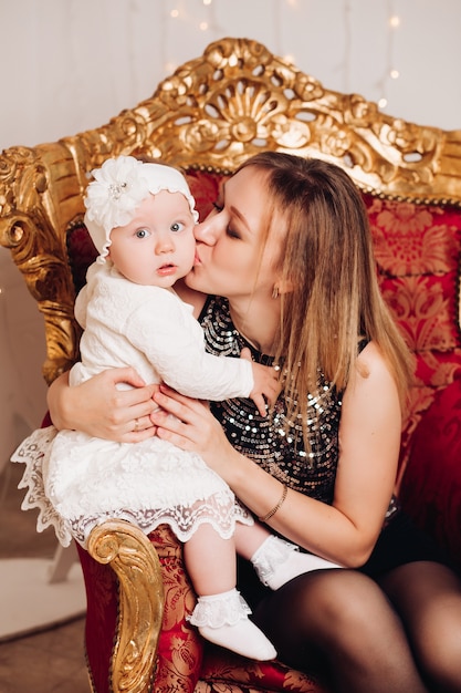 Cute little girl sitting with mother. Christmas time.