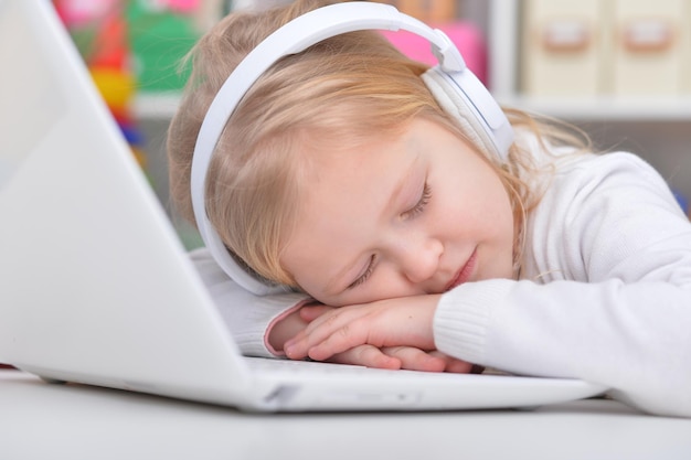 Cute little girl sleeping near laptop