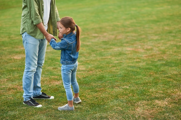 Cute little girl spending time with her father playing having fun in the beautiful green park on a