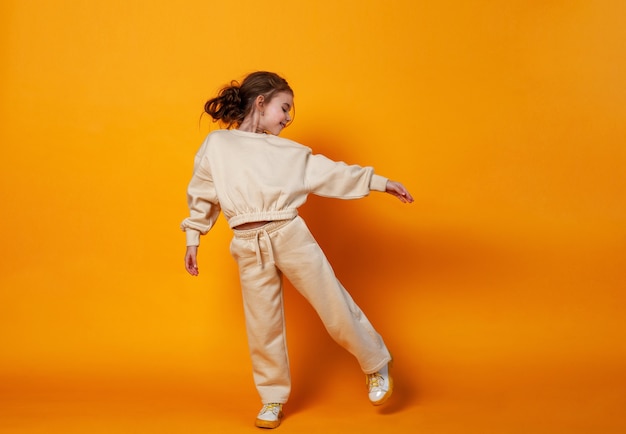 Cute little girl staying on a yellow background Space for text