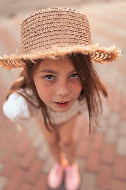 Cute little girl in a straw hat outdoors in summer