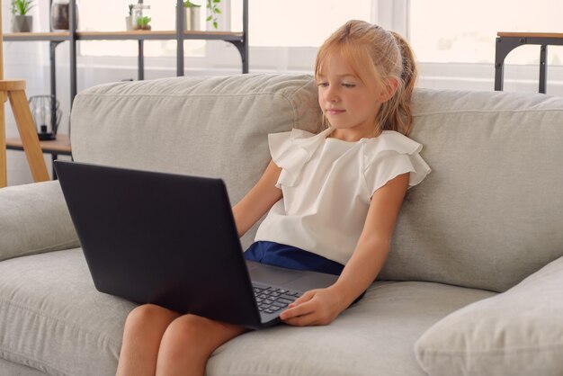 cute little girl student doing homework at home online