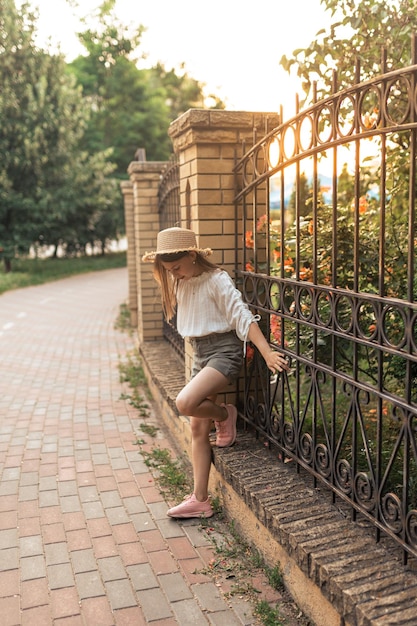 Cute little girl in the summer in the yard with a straw hat