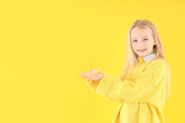 노란색 배경에 스웨터를 입은 귀여운 소녀