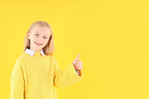 Bambina sveglia in maglione su sfondo giallo