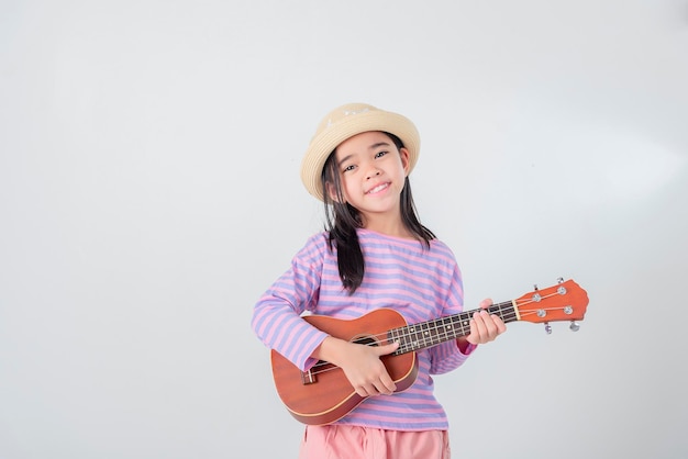 Cute little girl in swimsuit playing ukulele Happy vacation concept