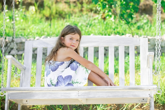 Cute little girl on a swing Smiling child playing outdoors in summer Happy mother swinging daughter at the park Child chill and resting in summer holiday