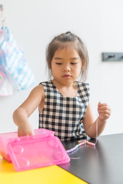 Cute little girl threading beads and making bracelet