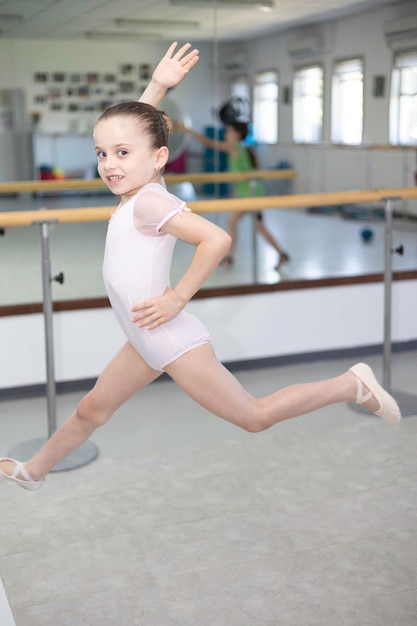 Photo cute little girl toddler ballerina in pale pink tutu and ballet shoes practicing dance jump.