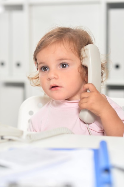 Cute little girl using phone in office