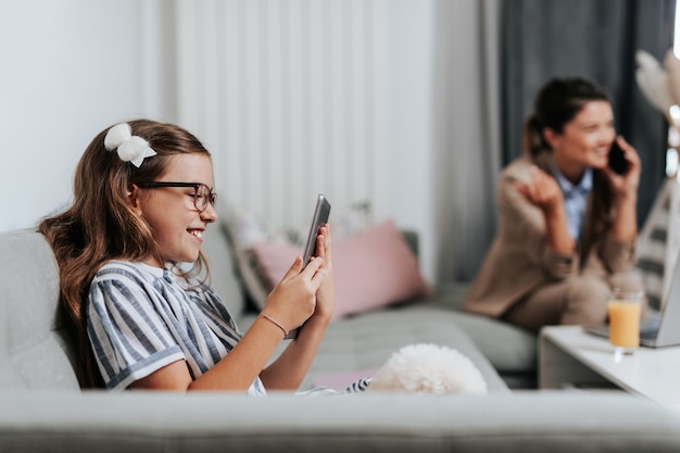 Милая маленькая девочка смотрит онлайн школьный класс на своем планшете. Социальное дистанцирование и образ жизни, связанный с Covid-19 или коронавирусом.