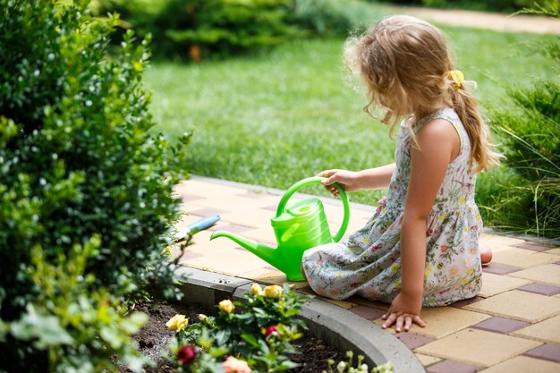 Cute little girl watering plants in the garden.