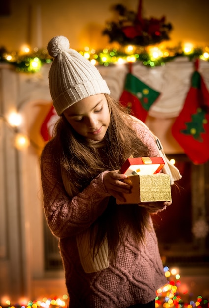 Cute little girl wearing sweater looking in gift box at Christmas eve