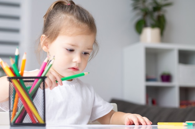 Cute little girl in a white t-shirt drawing