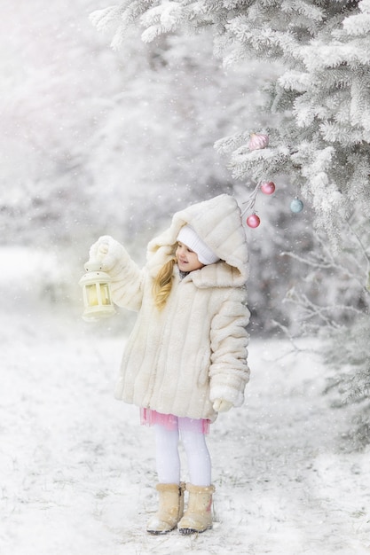 Cute little girl in the winter on the street before the new year in the snow