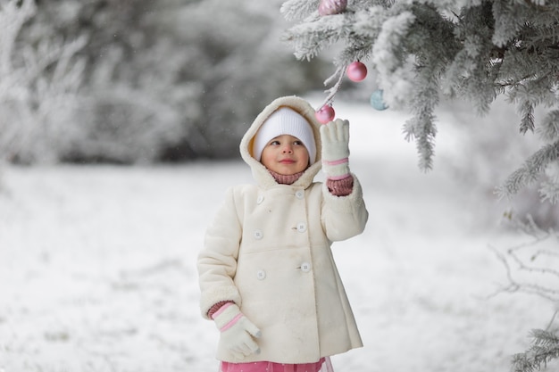 Bambina carina in inverno per strada prima del nuovo anno nella neve