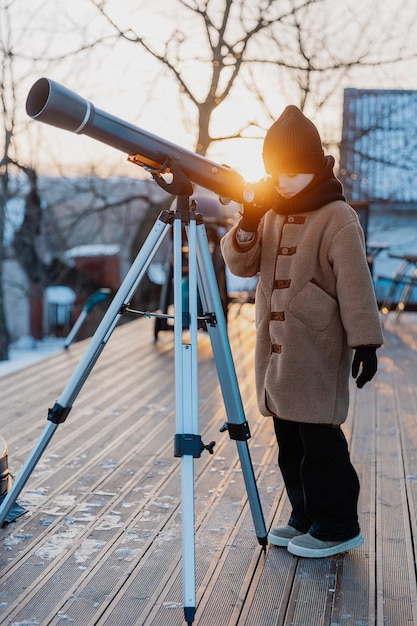 cute little girl with astronomical telescope stargazing under sunny sky