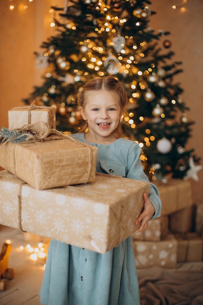 Cute little girl with christmas presents by the christmas tree