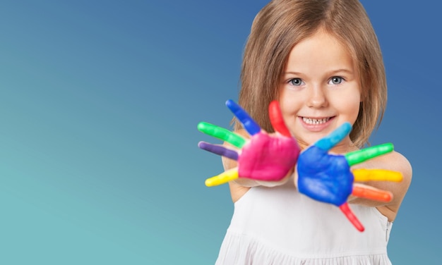 Cute little girl with colorful painted hands on blue background