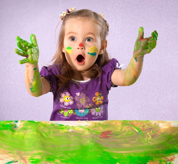 Cute little girl with colorful painted hands and face