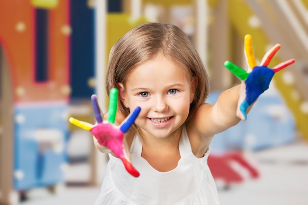 Cute little girl with colorful painted hands on light background