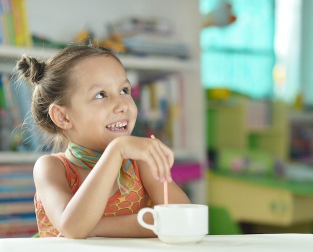 Cute little girl with cup  on the table