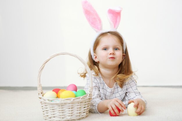 Bambina carina con cesto di pasqua su sfondo chiaro