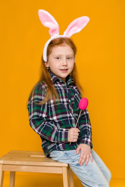 Cute little girl with easter bunny ears holding colorful eggs